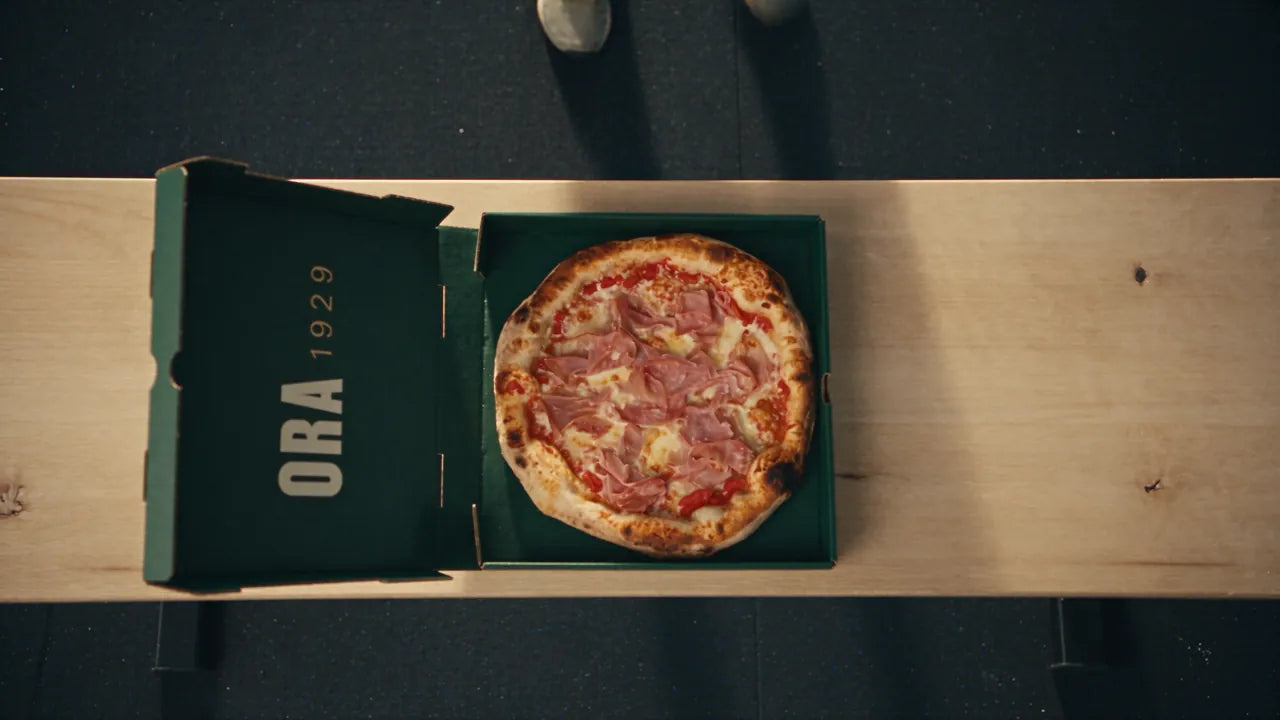 Athlète qui ouvre une boîte ORA et mange une pizza